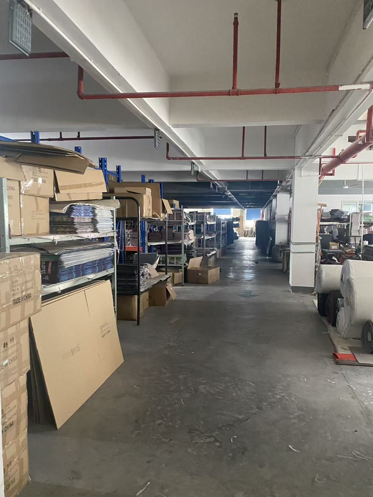 Warehouse aisle with shelving, cartons and finished fabric rolls