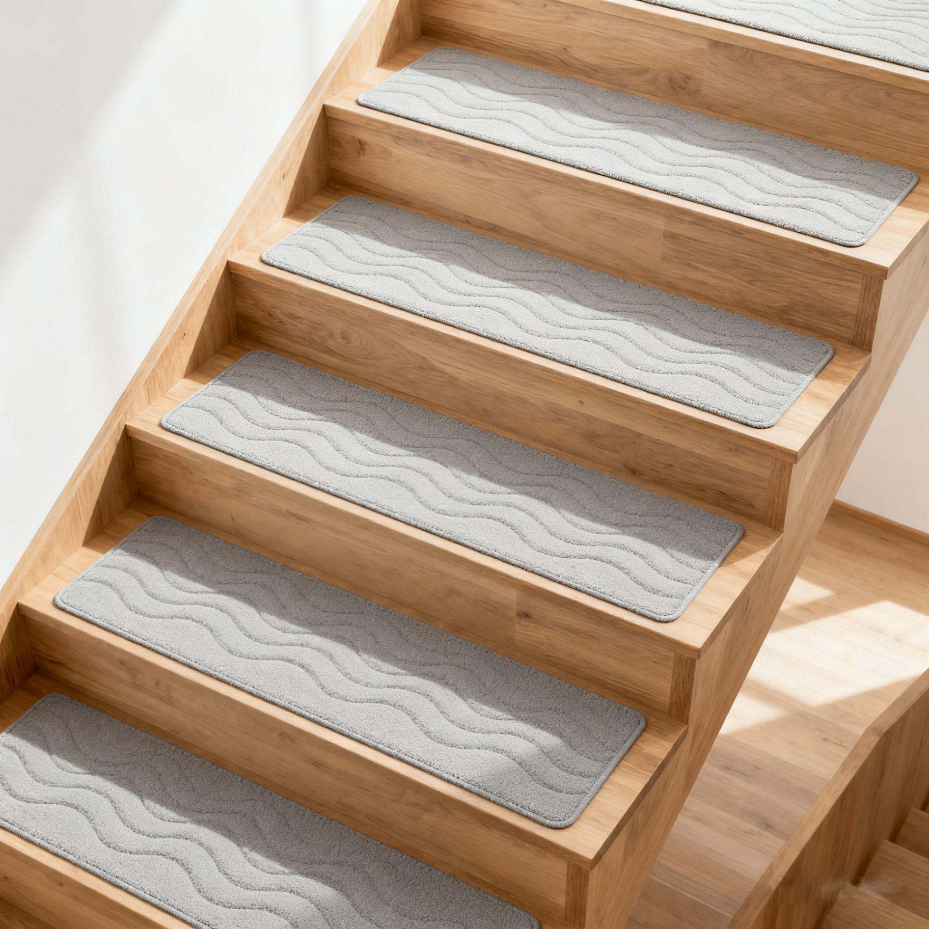 Grey wave-pattern stair tread mats on a light oak staircase